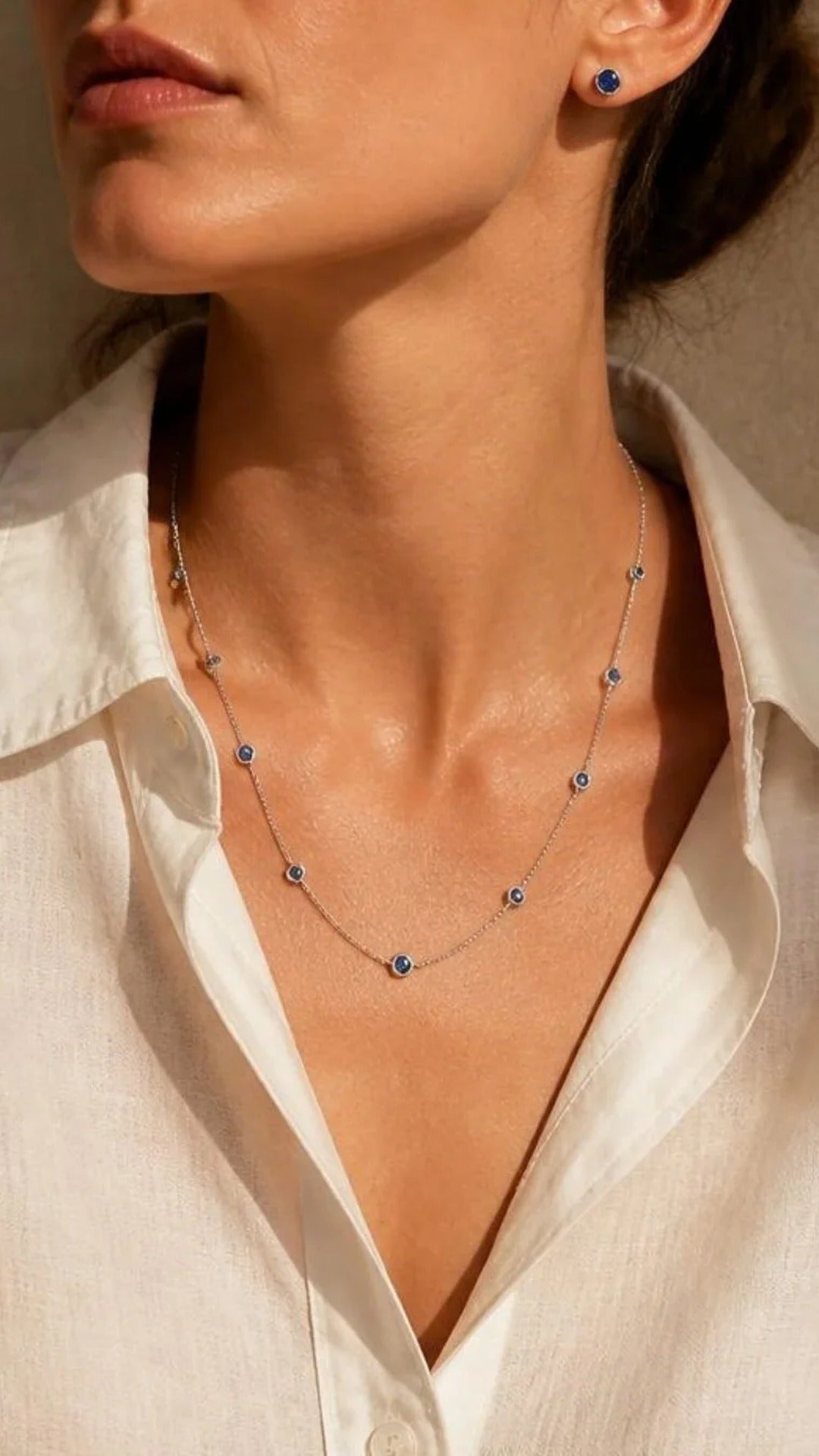 Woman in white linen shirt wearing Monaco sapphire strand necklace and studs